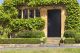 Brown wooden doors to traditional English stoned cottage, garden